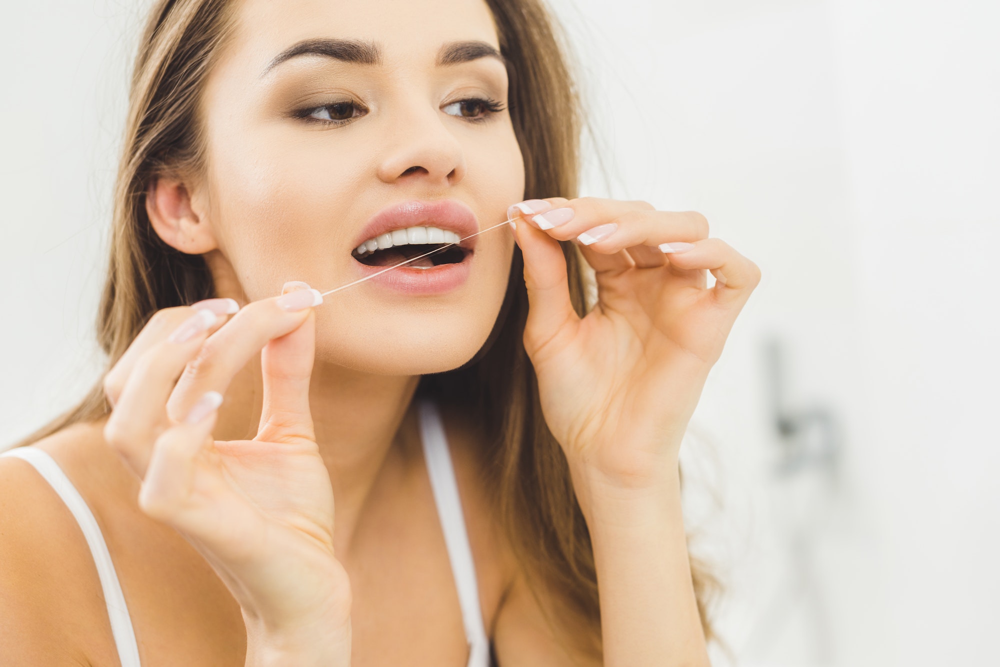 portrait of beautiful woman cleaning teeth with dental floss