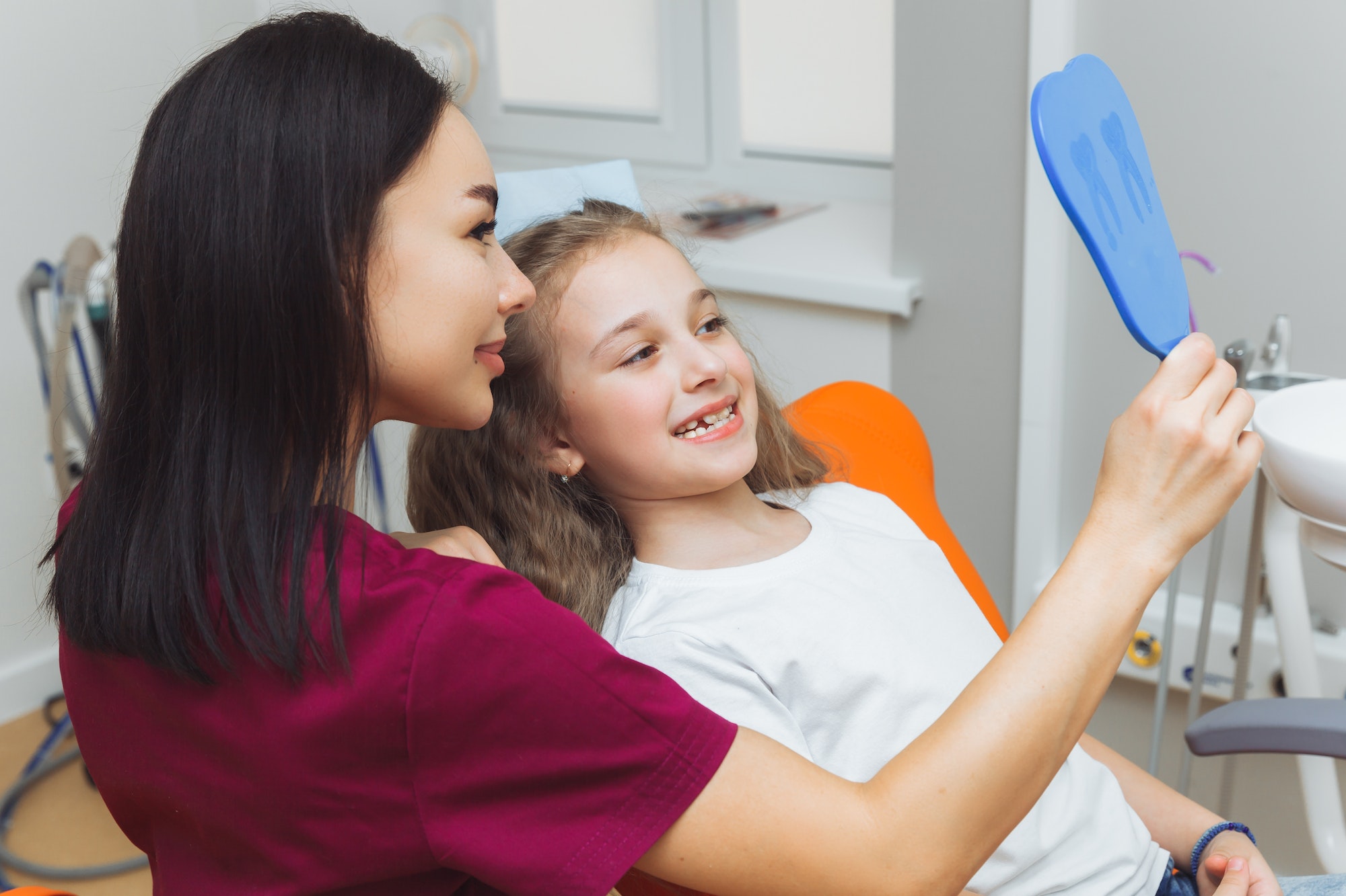 Side view portrait of little girl looking at mirror in pediatric dentistry after dental surgery.