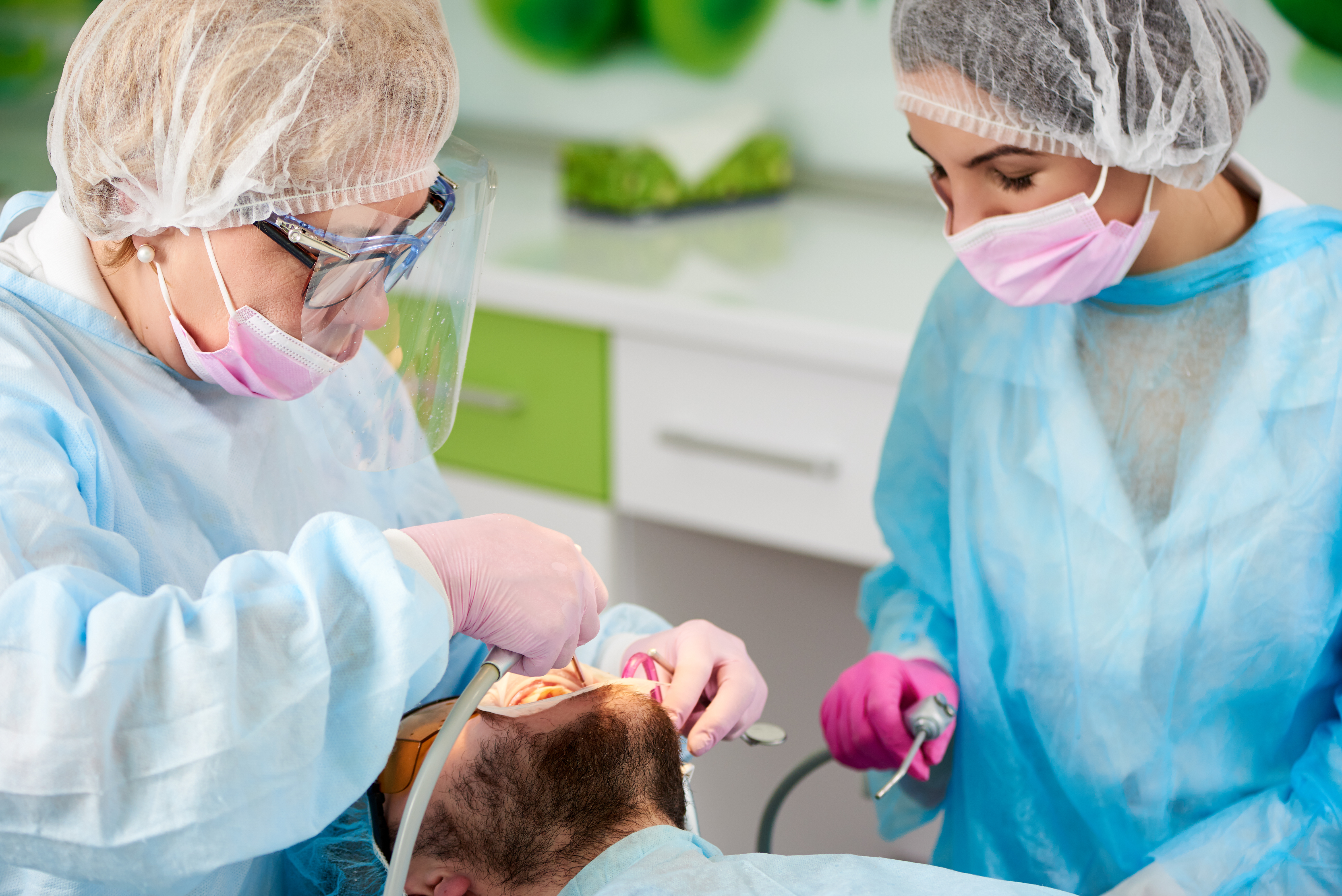 Dentist and her assistant in one-time form do tooth cleaning patient's teeth