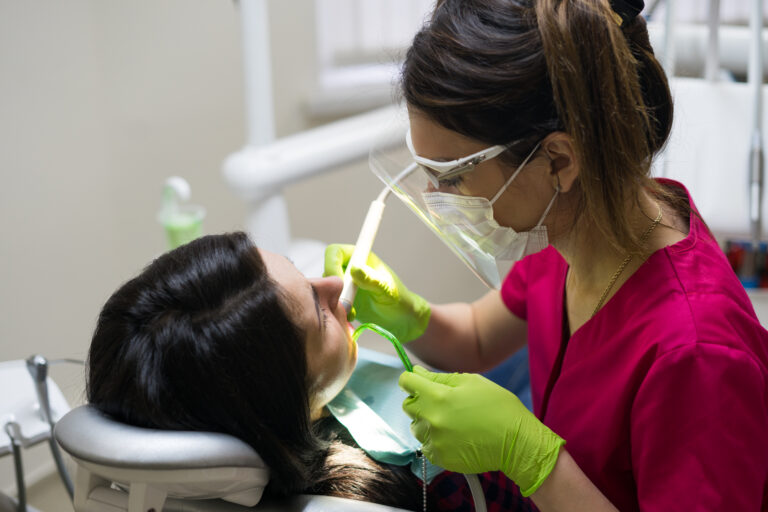 Female dentist cleaning teeth of patient